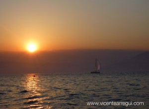 Algunos veleros se dirigen a la costa al caer el sol